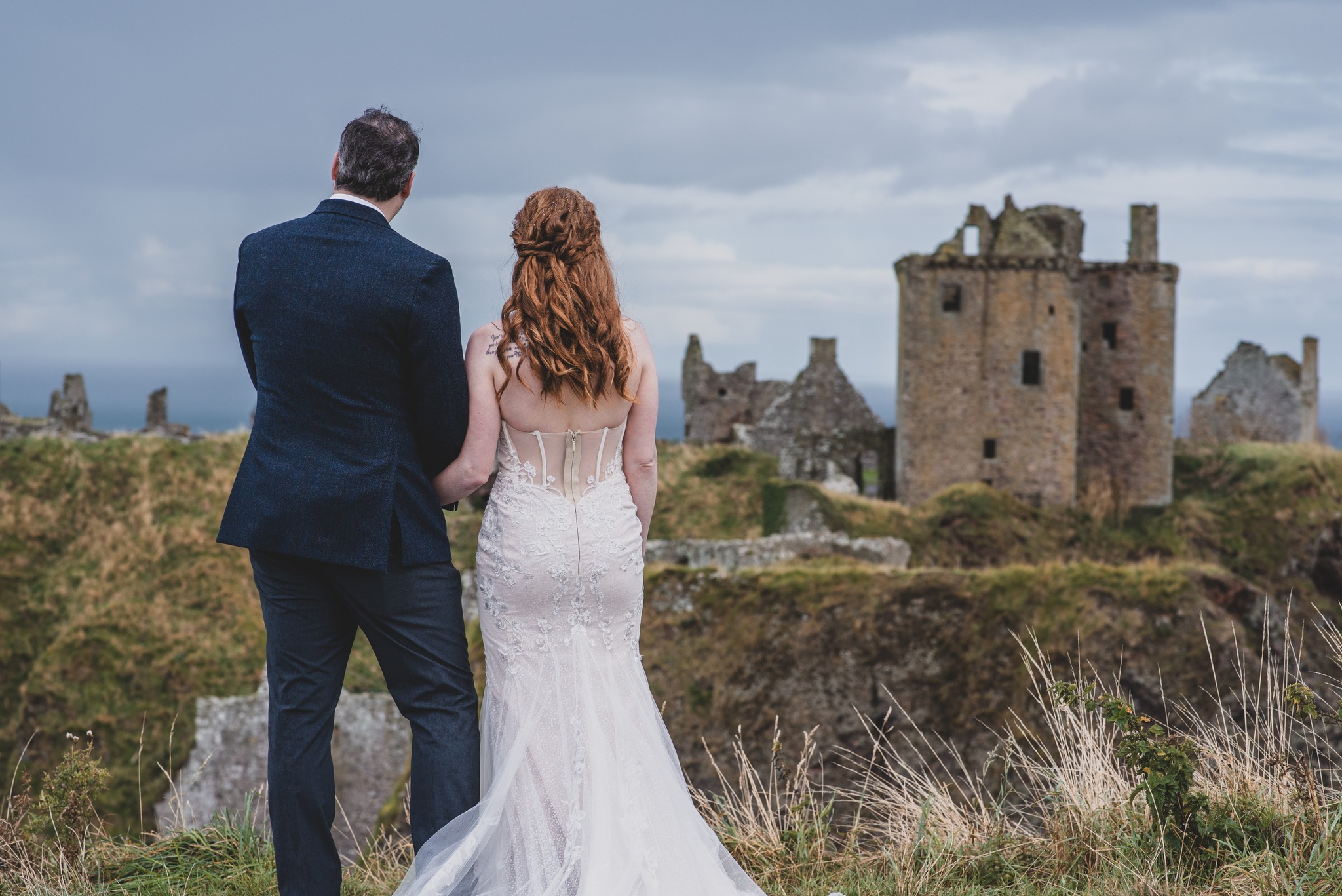 Bride and groom looking over to a castle in Stonehaven